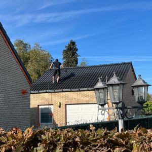Werker staat op dak tijdens het aanbrengen van coating
